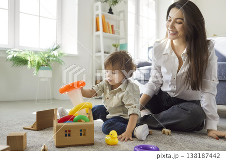 Young happy mother playing with toys with cute little child boy sitting on floor at home Young happy mother playing with toys with cute little child boy sitting on floor at home 138187442
