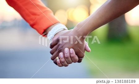 Interracial couple, holding hands and love in nature for support, trust or unity together. Closeup of people touching in romance, care or friendship walk in an outdoor park for partnership or duo 138188189
