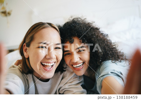 Love, selfie and portrait of lesbian couple on bed for bonding, resting or relaxing together. Smile, happy and young interracial lgbtq women taking a picture in bedroom of modern apartment or home. Love, selfie and portrait of lesbian couple on bed for bonding, resting or relaxing together. Smile, happy and young interracial lgbtq women taking a picture in bedroom of modern apartment or home. 138188459