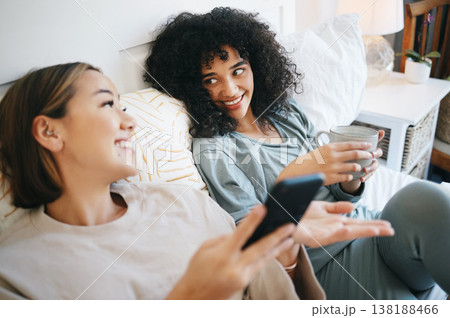 Phone, coffee and lesbian couple on bed in conversation for bonding, relaxing and resting together. Happy, communication and young lgbtq women networking on cellphone with latte in bedroom at home. Phone, coffee and lesbian couple on bed in conversation for bonding, relaxing and resting together. Happy, communication and young lgbtq women networking on cellphone with latte in bedroom at home. 138188466
