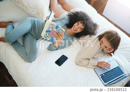 Laptop, morning and a lesbian couple relax in bed while together in their home on the weekend. Reading, computer and book with happy lgbt woman with her girlfriend in the bedroom from above for love 138188522