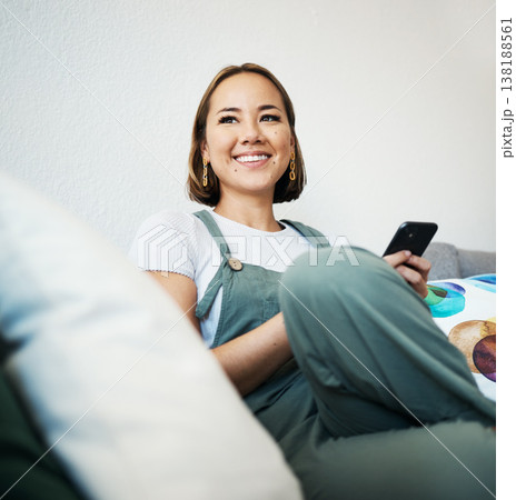 Woman, phone and thinking on couch of home for social media, internet post or conversation with smile. Person, smartphone and happiness for communication, networking and connectivity with technology 138188561