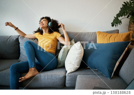 Happy, freedom and woman on a sofa with music, headphones or subscription at home. Podcast, earphones and female person having fun with radio, streaming or online audio, track or album in living room Happy, freedom and woman on a sofa with music, headphones or subscription at home. Podcast, earphones and female person having fun with radio, streaming or online audio, track or album in living room 138188628