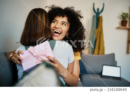 Excited, hug and present for birthday of girl friends and smile on living room sofa. Surprise, gift and happy female person at home with giving in lounge with celebration, congratulations and package 138188640