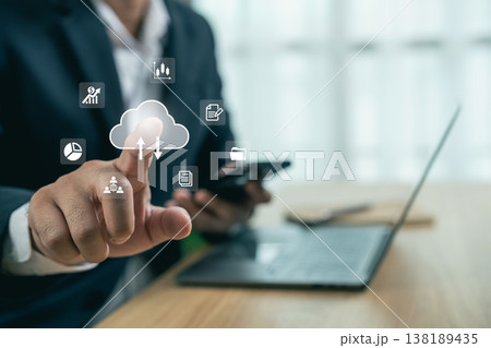 Business Professional Interacting with Cloud Technology and Data Analytics on a Modern Workspace with Laptop and Smartphone 138189435