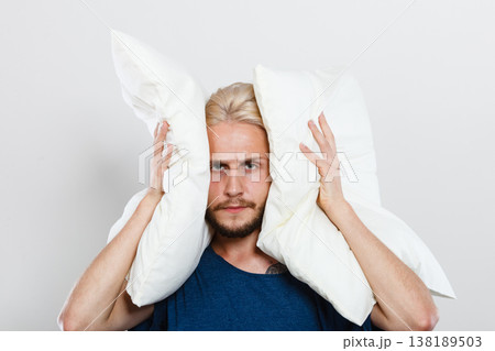 Sad man closing ears with pillows Sad man closing ears with pillows 138189503