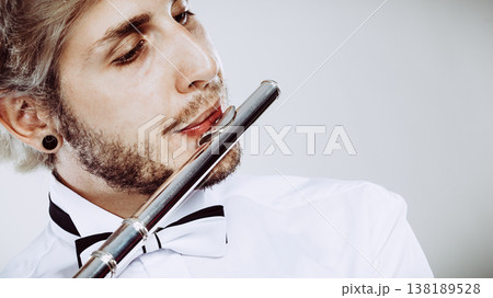 Male flutist playing his flute closeup Male flutist playing his flute closeup 138189528