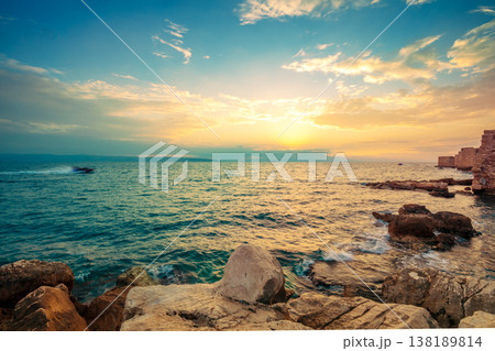 Seascape during sunset. Rocky seashore near Akko city in the evening, Israel. Sunset over the sea Seascape during sunset. Rocky seashore near Akko city in the evening, Israel. Sunset over the sea 138189814