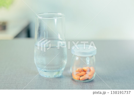Person Reaching for Vitamin Supplements with Water Person Reaching for Vitamin Supplements with Water 138191737