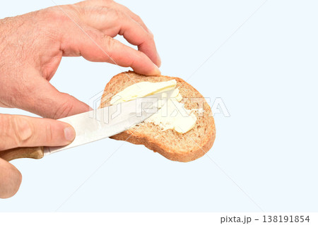 A man spreads butter on a slice of bread A man spreads butter on a slice of bread 138191854