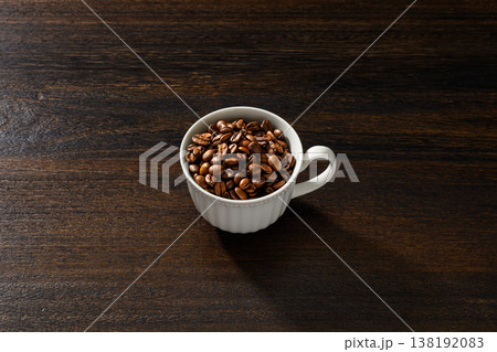 白いカップに入ったコーヒー豆と木目背景 白いカップに入ったコーヒー豆と木目背景 138192083