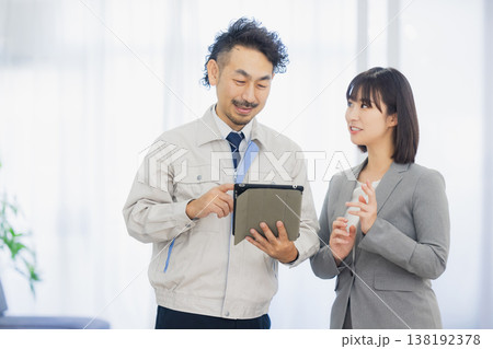 エアコンを見て不満そうな表情のビジネスウーマンと作業員　 138192378