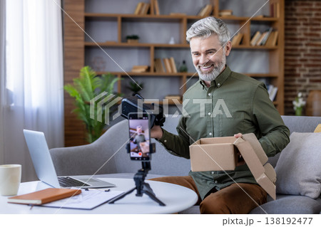 Senior man filming a video blog, reviewing new virtual reality glasses after unboxing them, creating content for social media and sharing his experience with modern technology 138192477