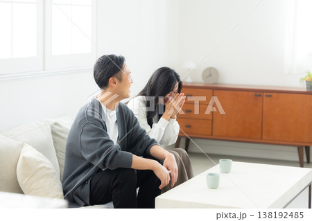 ソファーに座ってスマホを見る夫婦 ソファーに座ってスマホを見る夫婦 138192485