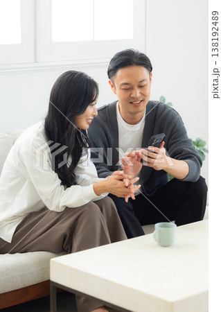 ソファーに座ってスマホを見る夫婦 ソファーに座ってスマホを見る夫婦 138192489