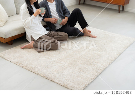 ソファーに座ってスマホを見る夫婦　 138192498