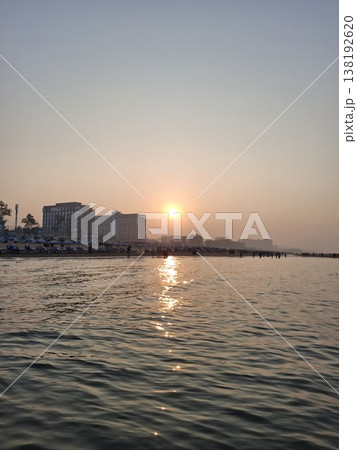 Serene Beach Sunset with Calm Waters and Silhouetted Cityline 138192620