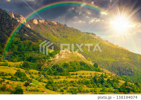 sunset over beautiful countryside. wonderful springtime landscape in mountains. grassy field and rolling hills. rural scenery with steep forested slopes. amazing highland under the rainbow 138194074