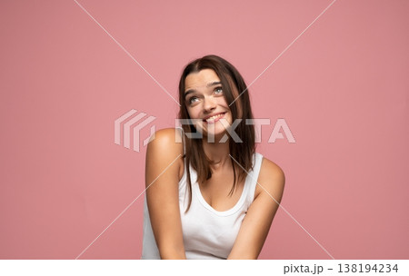 Young happy woman daydreaming and smiling, looking up with positive thoughts on pink background, feeling hopeful and thoughtful 138194234