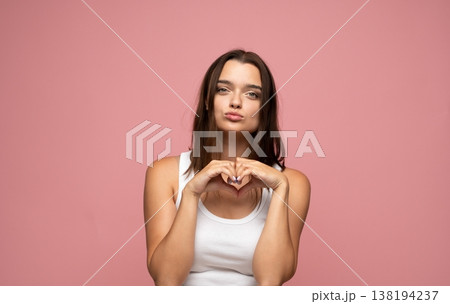 Young woman showing a heart with her hands, pouting her lips, expressing love, care, and romantic feelings Young woman showing a heart with her hands, pouting her lips, expressing love, care, and romantic feelings 138194237