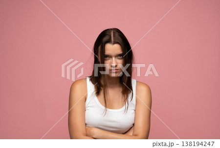 Young woman feeling frustrated and angry, crossing arms with a serious expression on a pink background Young woman feeling frustrated and angry, crossing arms with a serious expression on a pink background 138194247