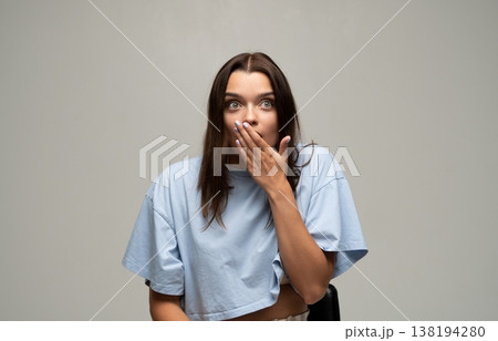 Young woman covering mouth with hand expressing shock and surprise, feeling disbelief or amazed by unexpected news Young woman covering mouth with hand expressing shock and surprise, feeling disbelief or amazed by unexpected news 138194280