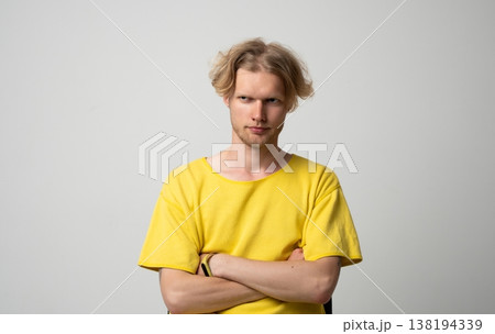 Young man showing distrustful and suspicious expression, raising eyebrow, feeling skeptical, doubting, questioning, and having arms crossed in studio portrait with negative emotions 138194339