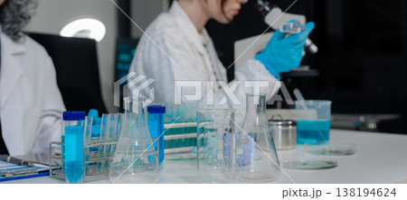 Team of biochemical research scientists working with a microscope for vaccine development in pharmaceutical research labeling. 138194624
