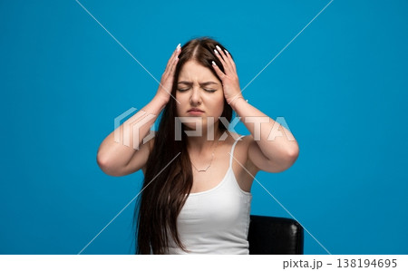 Young woman is having a headache, closing eyes and pressing hands to her head due to severe pain and migraine Young woman is having a headache, closing eyes and pressing hands to her head due to severe pain and migraine 138194695