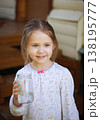 A village girl drinks water from a jar and smiles. 138195777