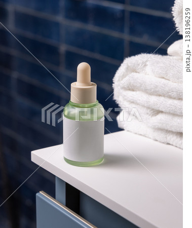 Dropper bottle with blank label near white bath towels in blue bathroom, cosmetic mockup Dropper bottle with blank label near white bath towels in blue bathroom, cosmetic mockup 138196259