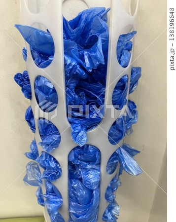 Blue shoe covers stored in a white container in a room with a simple setup 138196648