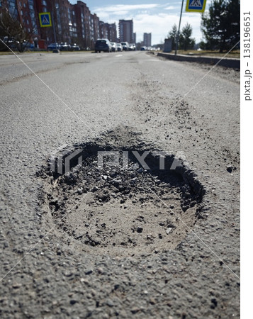 Pothole in city street with buildings and cars on a sunny day Pothole in city street with buildings and cars on a sunny day 138196651