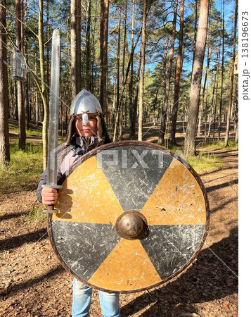Person holds a sword and shield while standing in a forest during daytime Person holds a sword and shield while standing in a forest during daytime 138196673