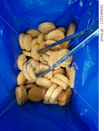 Food items placed in a blue container with metal tongs for serving 138196685