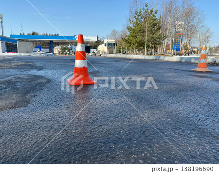 Traffic cones placed on a wet asphalt surface near a gas station on a sunny day Traffic cones placed on a wet asphalt surface near a gas station on a sunny day 138196690