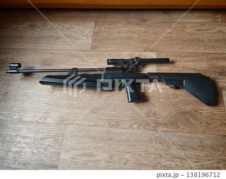 Black rifle displayed on wooden floor in indoor setting during daytime Black rifle displayed on wooden floor in indoor setting during daytime 138196712