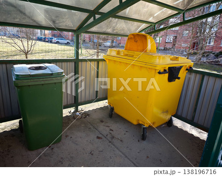 City waste collection area with green and yellow bins during the day 138196716