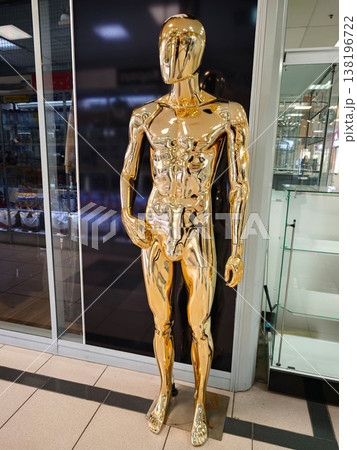 Gold mannequin stands in a store near a display window in a shopping area 138196722