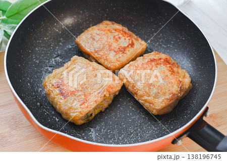 豚挽肉と野菜を詰めた揚げをフライパンで焼く 138196745