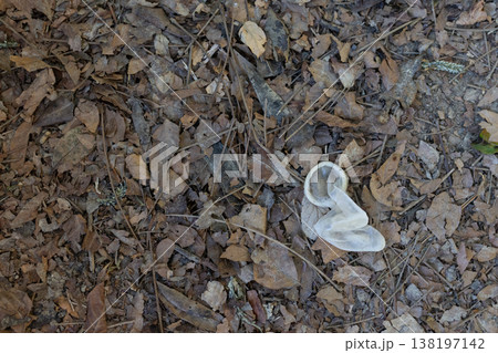 Used condom lying on ground among dry leaves 138197142