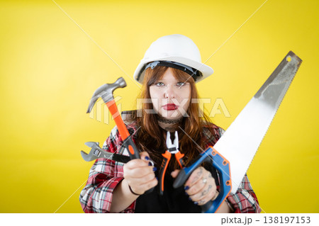 Confident female builder holding essential construction repair tools 138197153