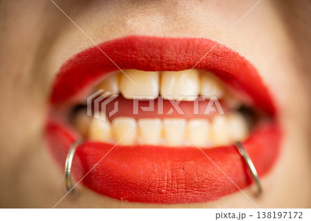 Person with red lipstick showing teeth and lip rings 138197172