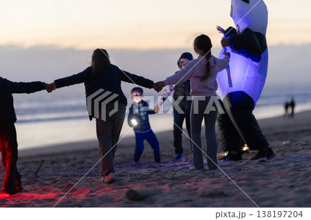 Kids holding hands dancing at evening beach party 138197204