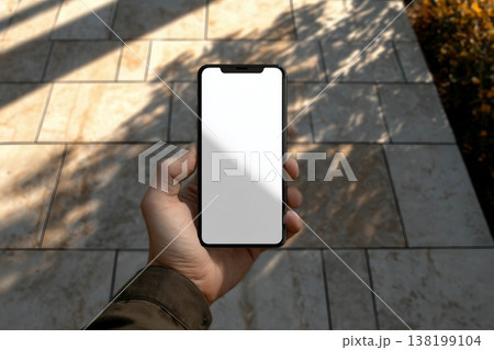 Man holding smartphone mobile device mockup template in an urban outdoor environment with sharp sunlit shadows. Isolated surface to place your design. Man holding smartphone mobile device mockup template in an urban outdoor environment with sharp sunlit shadows. Isolated surface to place your design. 138199104