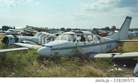 Eerie field filled with several abandoned small airplanes, all in various states of disrepair, overgrown with grass under a cloudy sky. 138200575