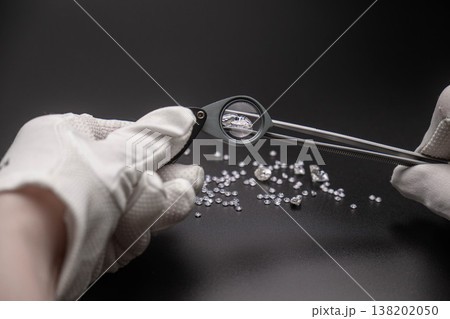Close-up: jeweler examines small diamonds with magnifier and tweezers Close-up: jeweler examines small diamonds with magnifier and tweezers 138202050