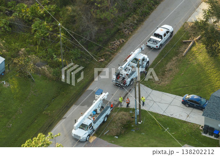 Electrician workers repairing damaged power lines using bucket trucks after hurricane Ian in Florida residential area 138202212