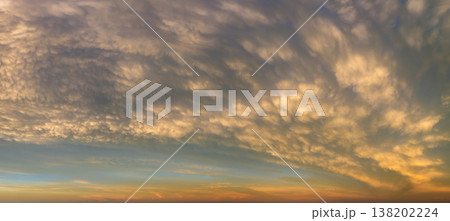 Dramatic sunset sky covered with colorful yellow clouds. Panoramic skyscape 138202224
