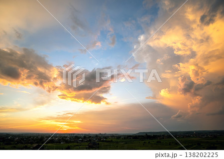 Dramatic sunset rural landscape with puffy clouds lit by orange setting sun and blue sky. Dramatic sunset rural landscape with puffy clouds lit by orange setting sun and blue sky. 138202225